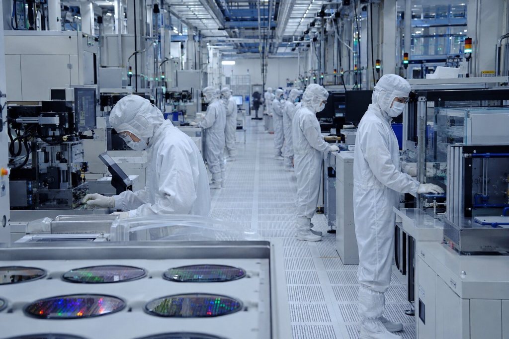 Técnicos trabajan en una línea de fabricación de semiconductores dentro de una sala limpia