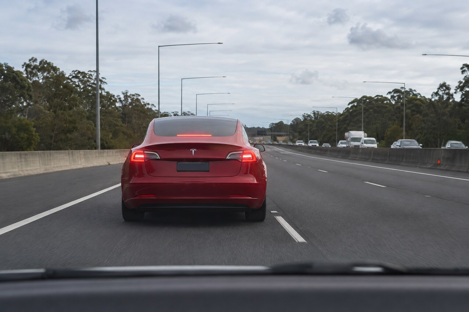 Tesla rojo con las luces de freno activadas en una autopista sin obstáculos visibles